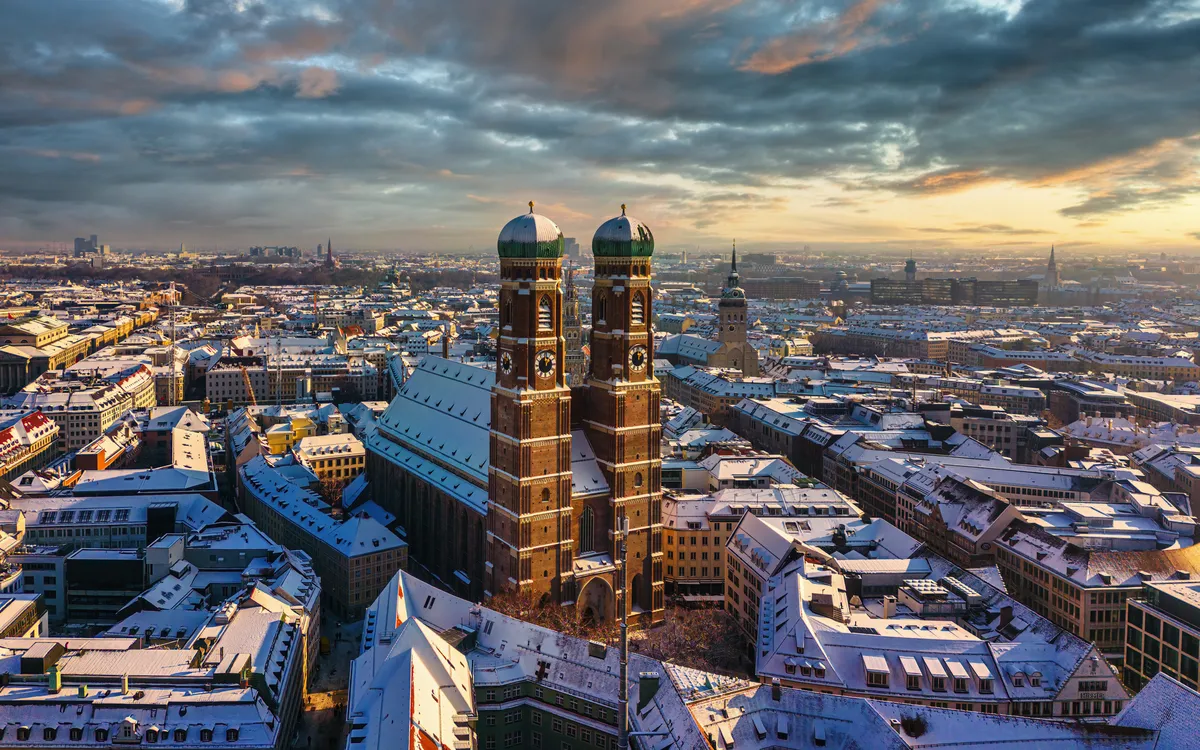 Verschneite Stadtansicht von München mit der Frauenkirche im Zentrum.