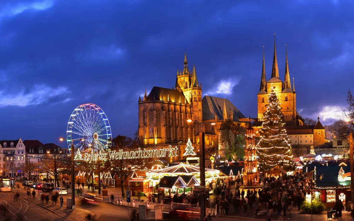 Weihnachtsmarkt in Erfurt bei Abenddämmerung mit Dom und Riesenrad im Hintergrund