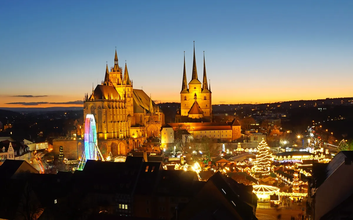 Weihnachtsmarkt bei Dämmerung vor dem Domplatz mit beleuchteten Buden und Riesenrad.
