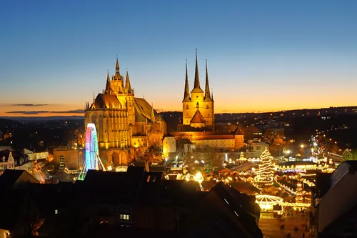 Weihnachtsmarkt bei Dämmerung vor dem Domplatz mit beleuchteten Buden und Riesenrad.