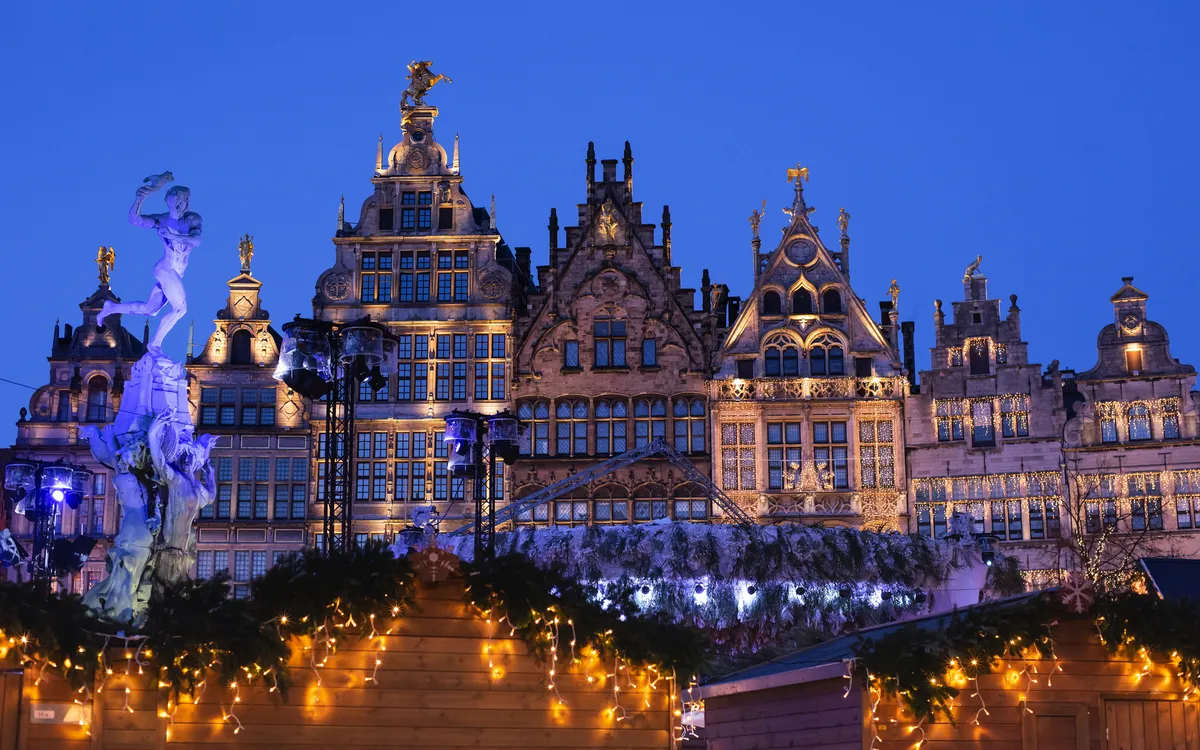 Historische Gebäude und Weihnachtsmarktlichter in Antwerpen bei Nacht.