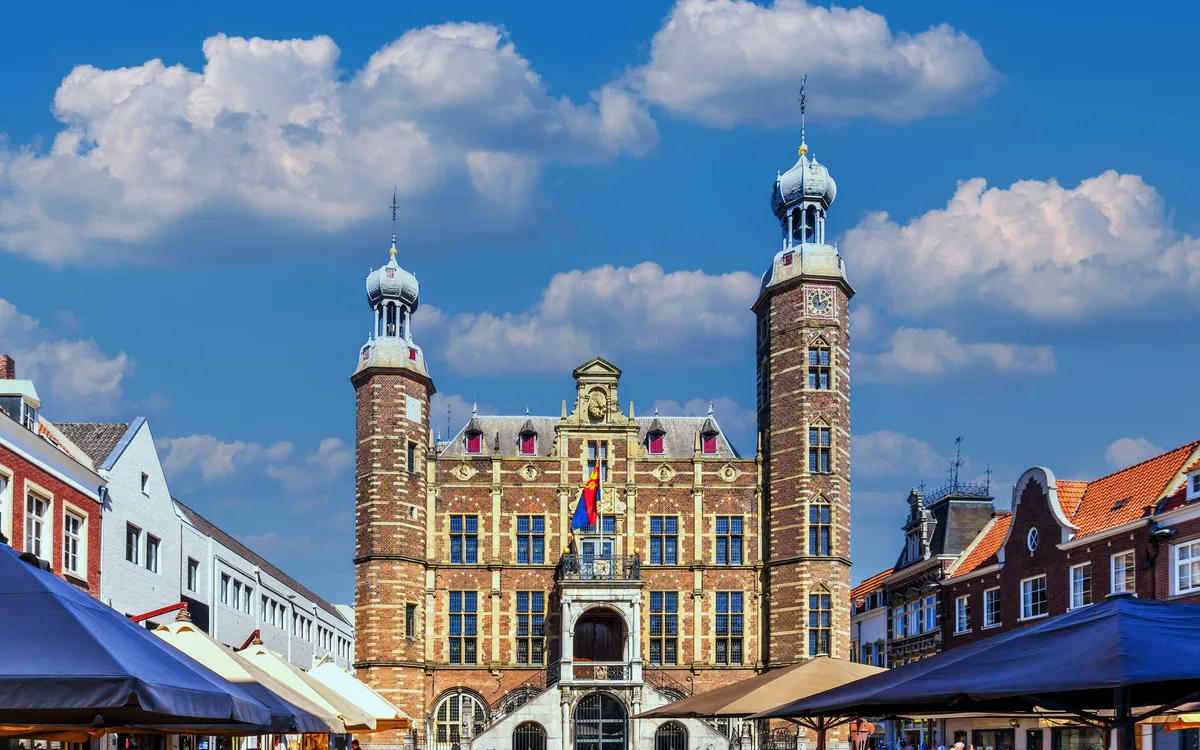 Historisches Rathaus mit Türmen und blauen Himmel im Hintergrund.