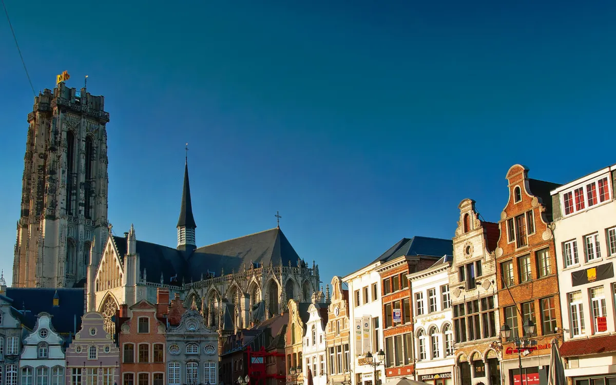 Historische Gebäude und ein Kirchturm unter klarem blauem Himmel.