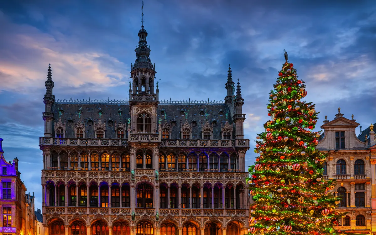 Historisches Gebäude und geschmückter Weihnachtsbaum bei Abenddämmerung.