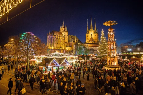 Menschen auf einem beleuchteten Weihnachtsmarkt in Erfurt bei Nacht.