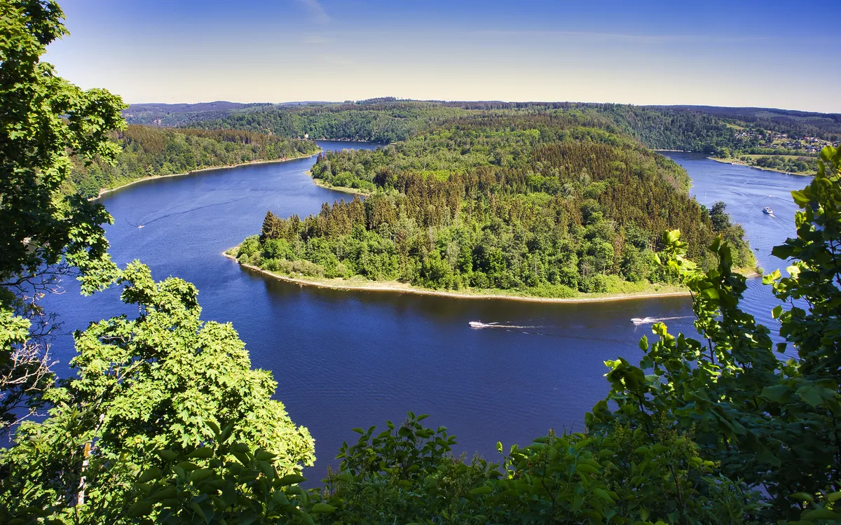 Flusslandschaft mit bewaldeter Insel und blauem Himmel im Hintergrund