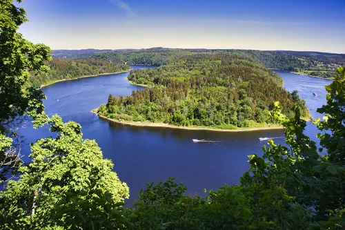 Flusslandschaft mit bewaldeter Insel und blauem Himmel im Hintergrund