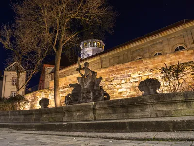 Statue beim Brunnen gegenüber dem Markgräflichen Opernhaus in Bayreuth bei Nacht im Winter.