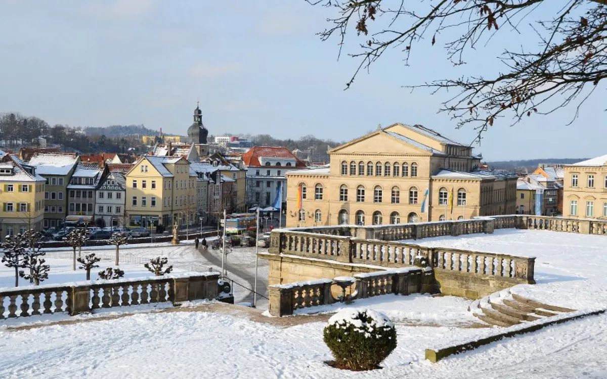 Verschneite Stadtansicht mit historischen Gebäuden und kahlen Bäumen.