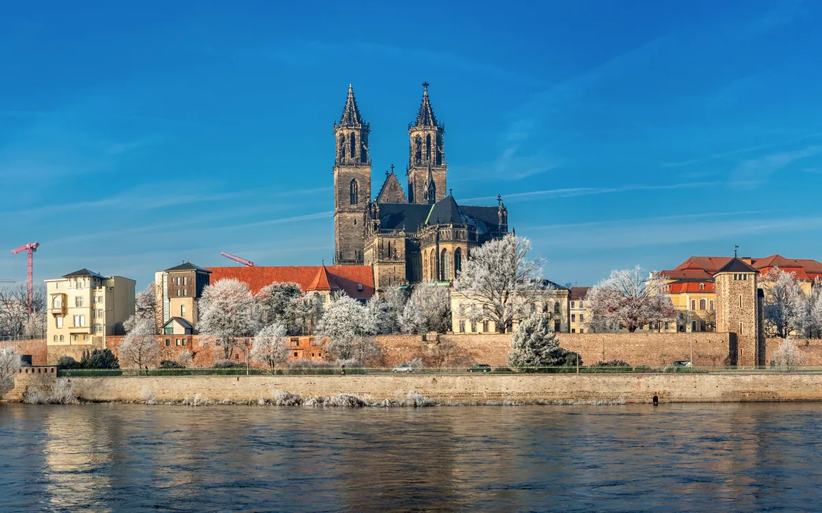 Winterliche Stadtansicht mit einer Kathedrale und Fluss im Vordergrund.