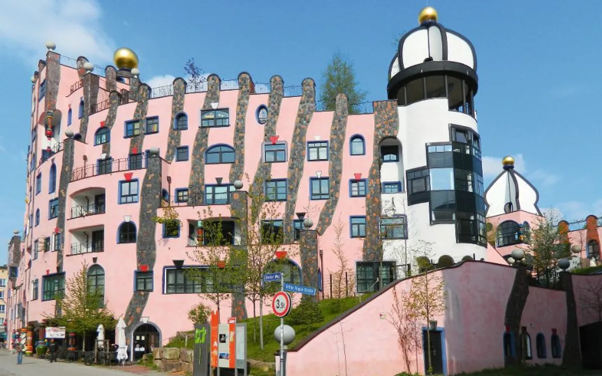 Hundertwasserhaus in Magdeburg mit rosa Fassade und unregelmäßigen Fenstern.
