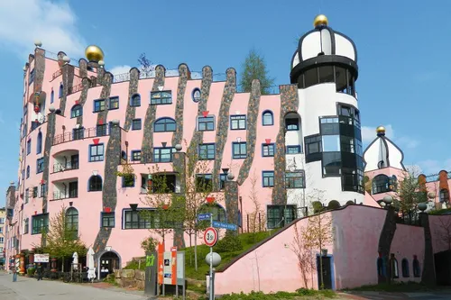 Hundertwasserhaus in Magdeburg mit rosa Fassade und unregelmäßigen Fenstern.