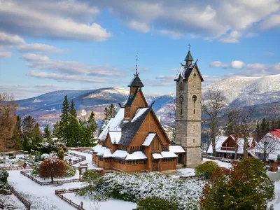 Holzkirche im Schnee mit Bergen im Hintergrund.