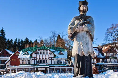 Statue vor schneebedeckten traditionellen Häusern und Bäumen im Winter.