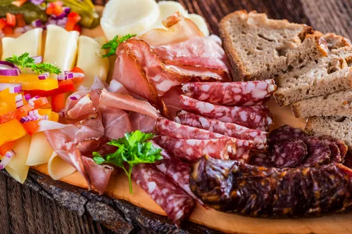 Wurst- und Käseplatte mit Brot auf einem Holzbrett serviert.