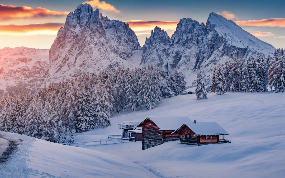 Verschneite Hütte in Berglandschaft bei Sonnenaufgang