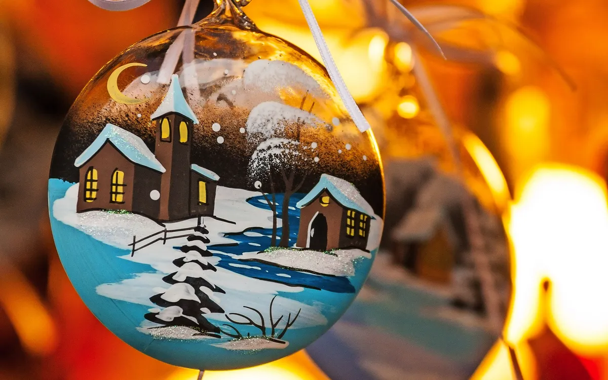Weihnachtskugeln mit Winterlandschaft und warmem Licht im Hintergrund.