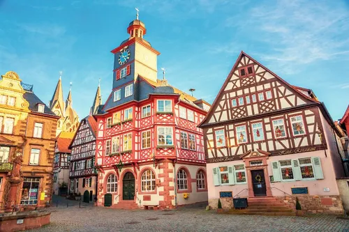 Historische Fachwerkhäuser mit Turm und Uhr in einer Altstadt.