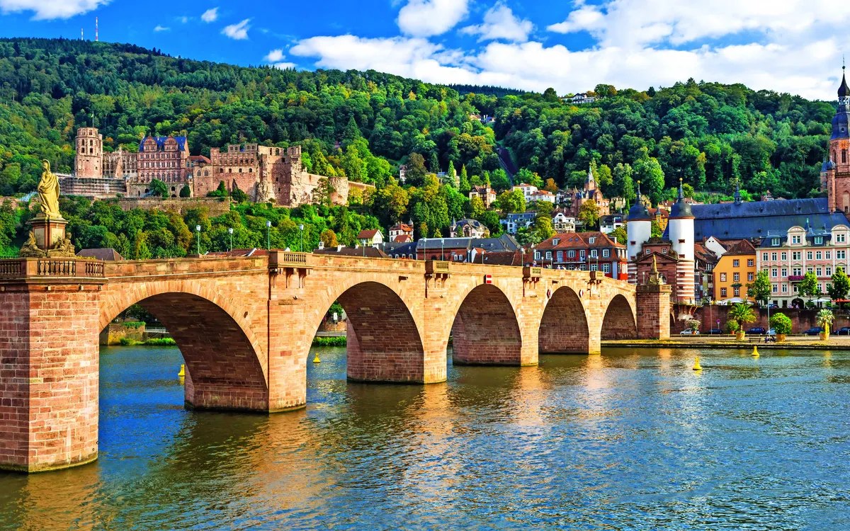 Alte Brücke in Heidelberg mit Schloss im Hintergrund, sonniger Tag.