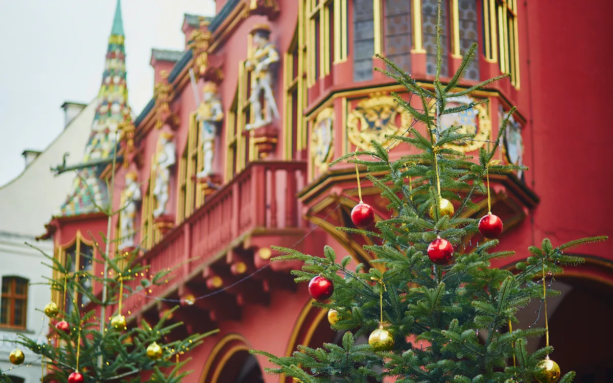 Zwei Weihnachtsbäume vor einem roten, verzierten Gebäude.