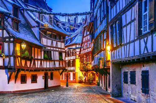 Fachwerkhäuser in einer malerischen, mit Kopfsteinpflaster gepflasterten Altstadtstraße bei Dämmerung.