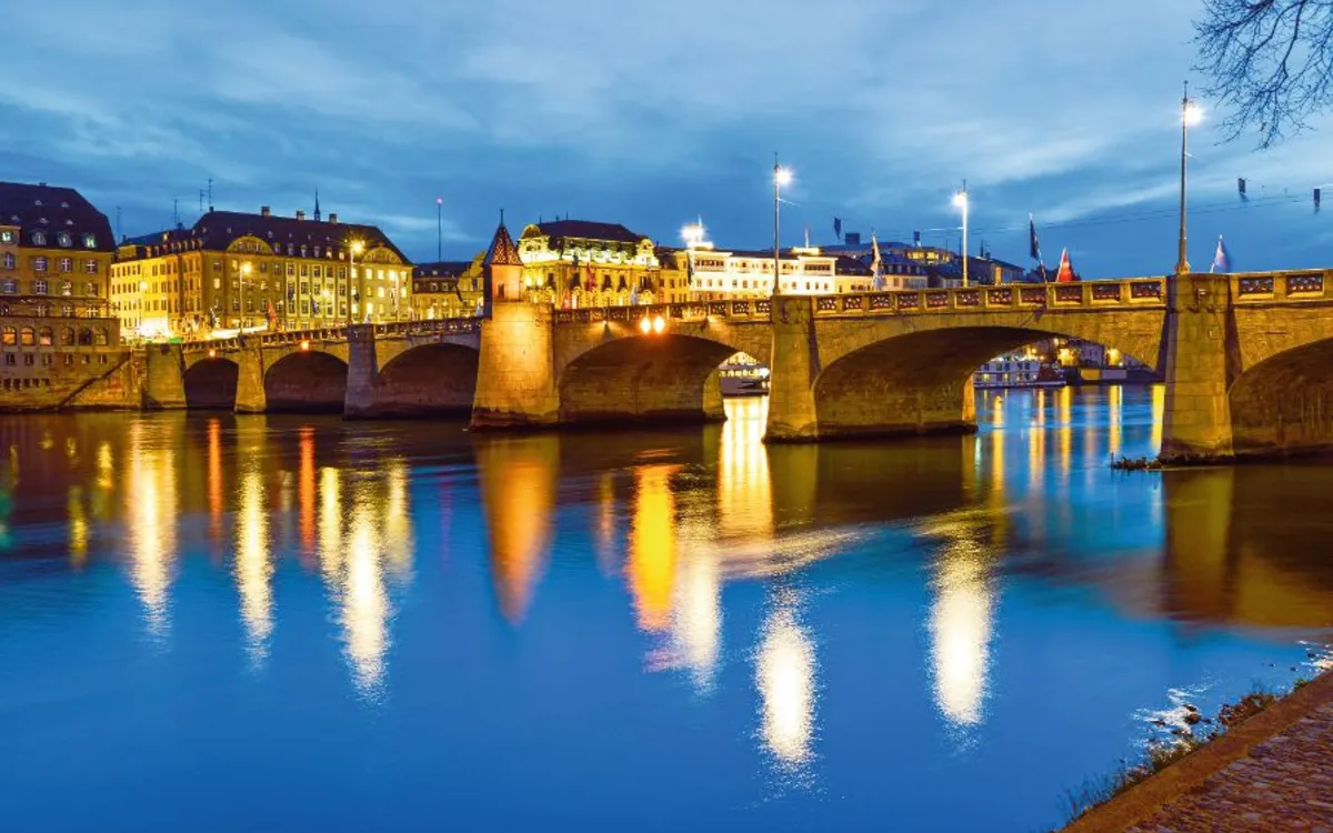 Brücke bei Nacht mit Lichtern, die sich im Wasser spiegeln.