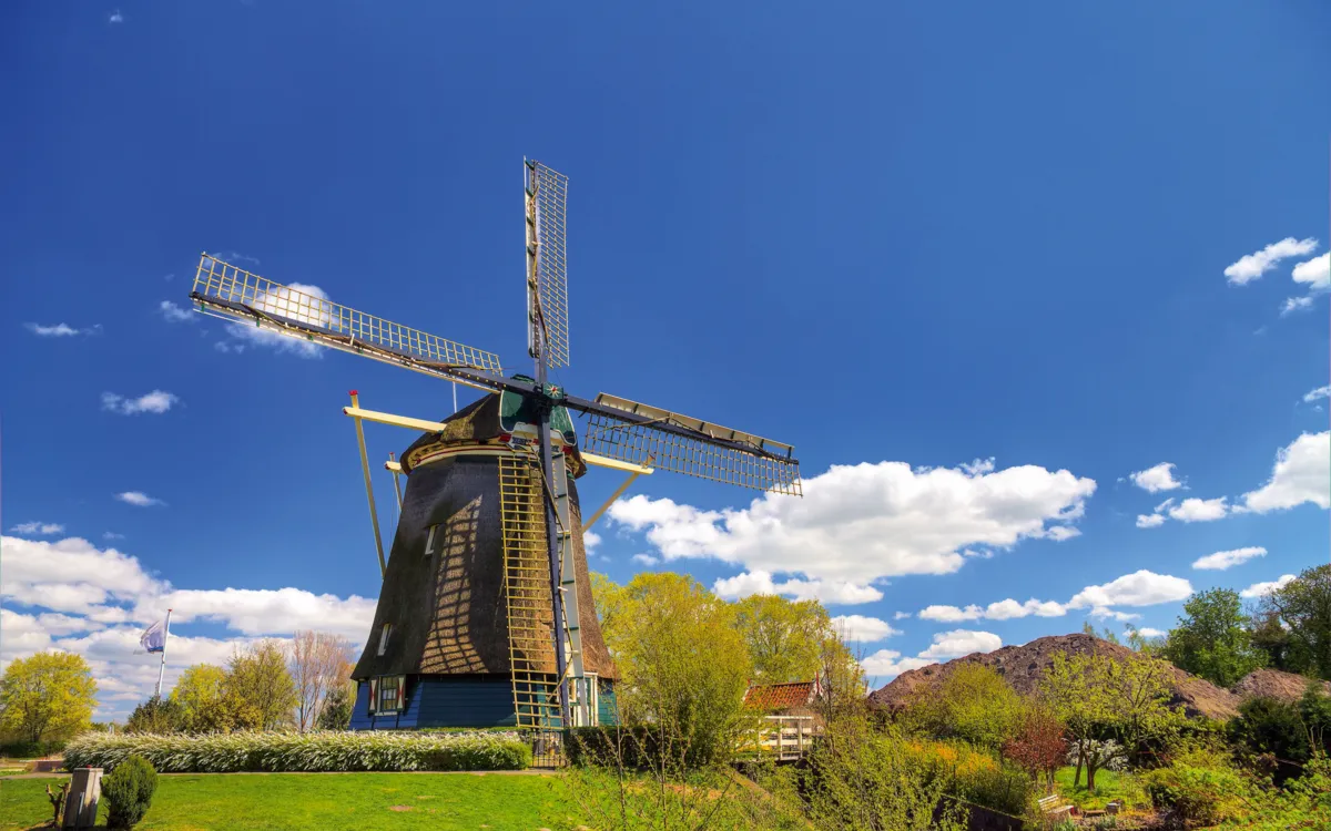 Holländer-Windmühle Riekermolen bei Amsterdam in ländlicher Landschaft unter blauem Himmel.