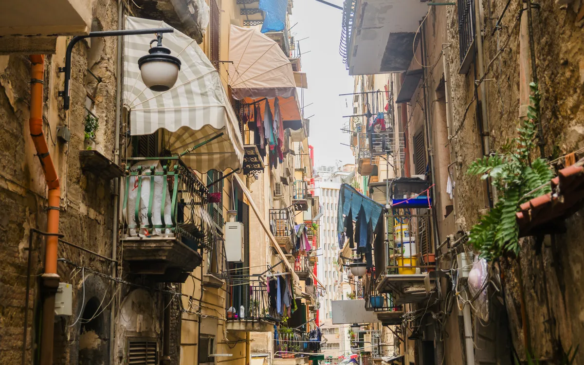 Schmale Gasse in der Altstadt von Neapel mit Wäscheleinen und alten Gebäuden.