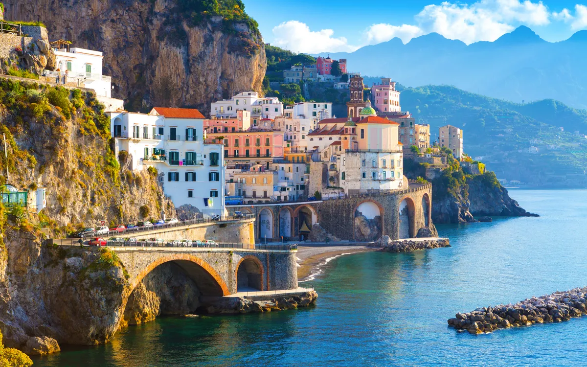 Atrani an der Amalfiküste mit bunten Häusern und steilen Felsen am blauen Meer.