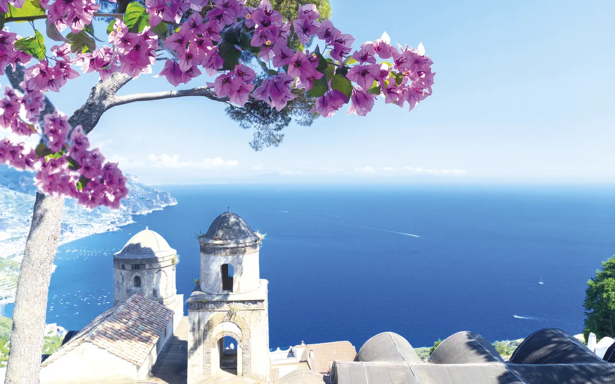 Blick auf das Meer und die Küste von Ravello, Italien, mit Blumen im Vordergrund.