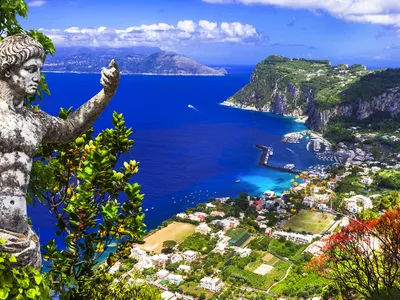 Panorama der Insel Capri mit Statue und Blick auf das blaue Meer und Steilhänge.