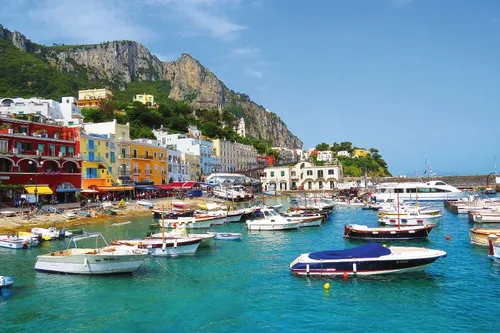 Boote im Hafen vor farbigen Gebäuden und Klippen auf der Insel Capri.