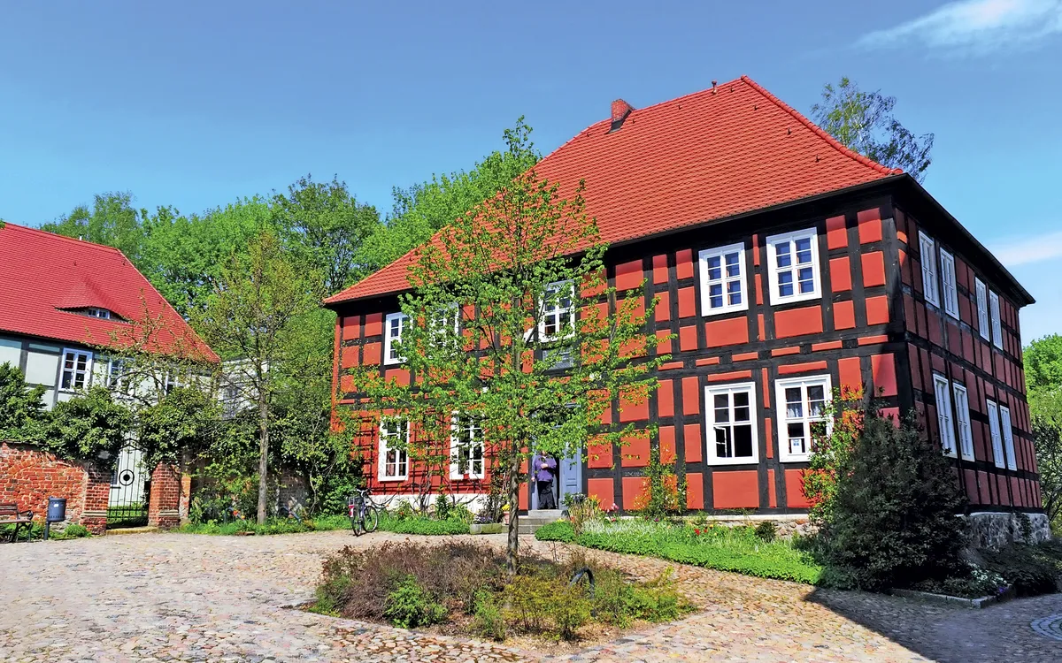 Fachwerkhaus mit rotem Dach und gepflastertem Hof in Bad Belzig.