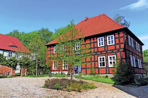 Fachwerkhaus mit rotem Dach und gepflastertem Hof in Bad Belzig.