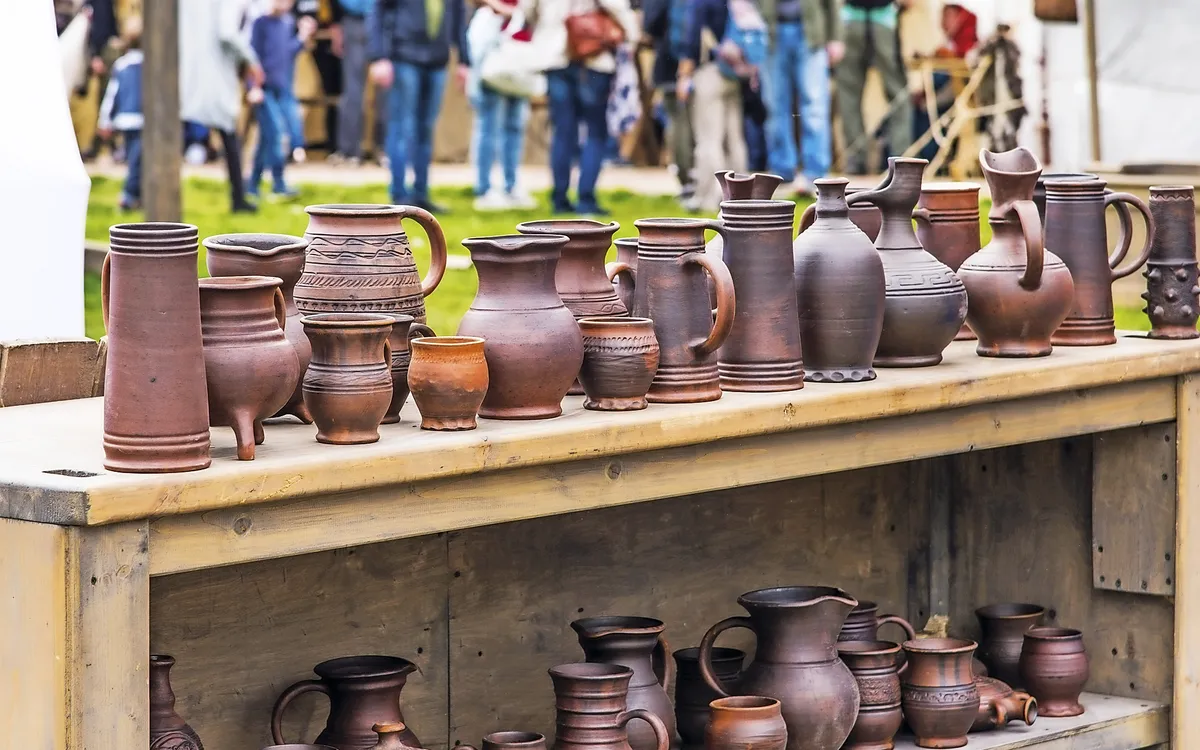 Töpferwaren auf Holztisch am Töpfermarkt im Freien ausgestellt.
