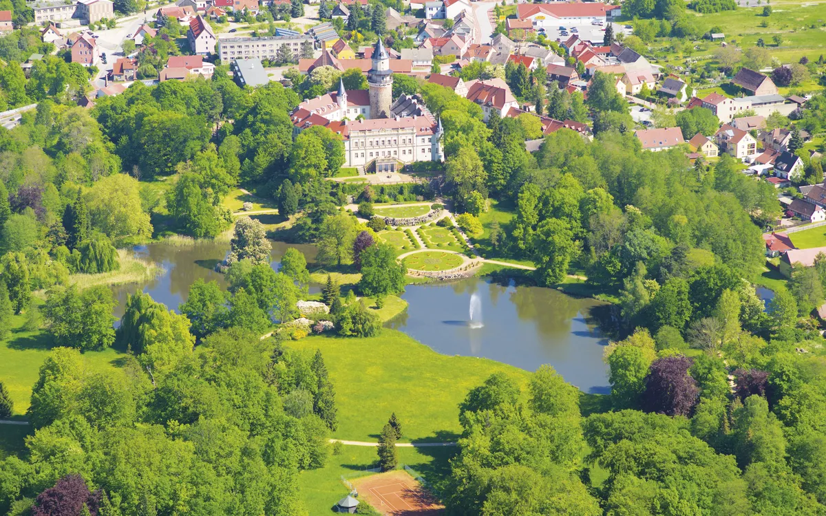 Schloss Wiesenburg umgeben von Parklandschaft aus der Vogelperspektive.