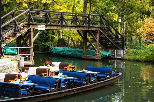 Boot für Kahnfahrt im Spreewald unter Holzbrücke, umgeben von Bäumen.