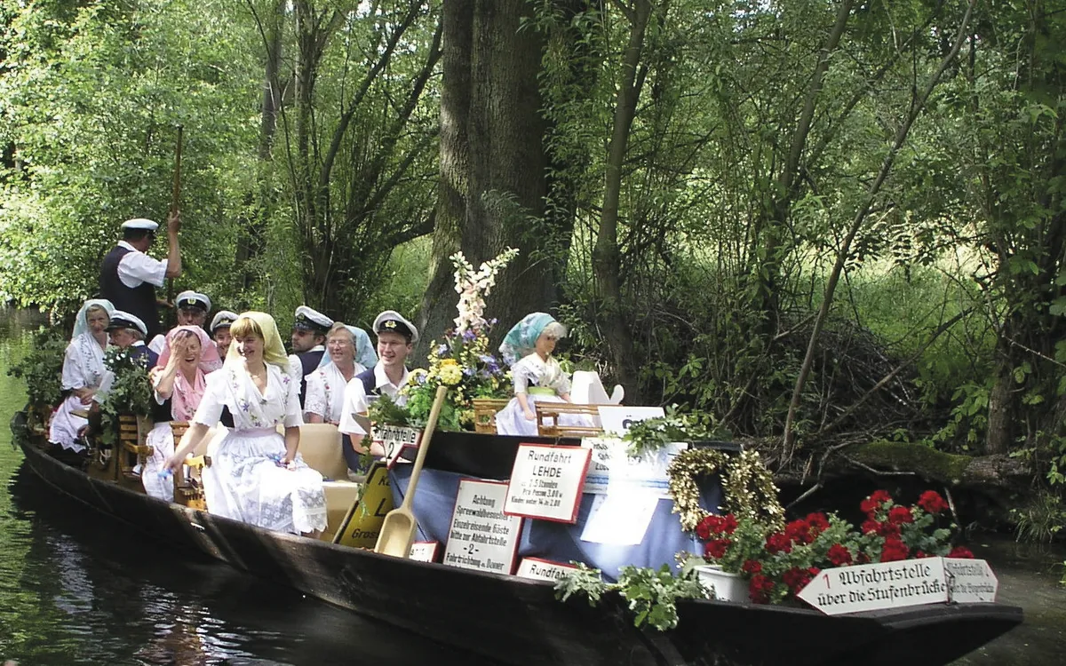 Menschen in Tracht auf traditionellem Spreewald-Kahn im Fluss.