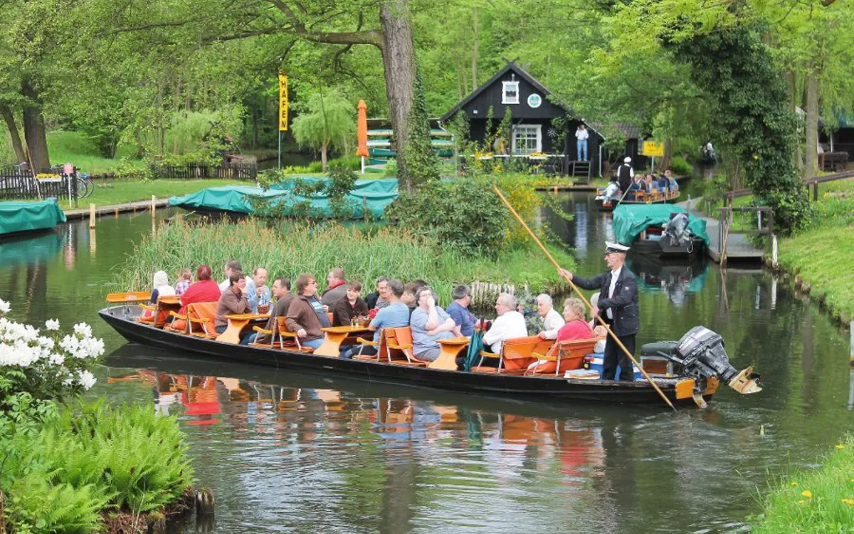 Menschen auf einem Kahn im Spreewald bei Lübbenau, umgeben von grüner Natur.