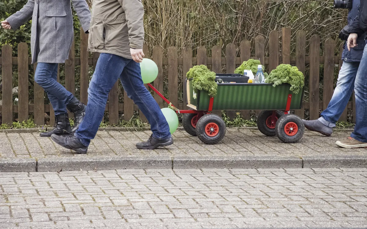 Personen ziehen einen Bollerwagen mit Grünkohl bei einer Winterwanderung.