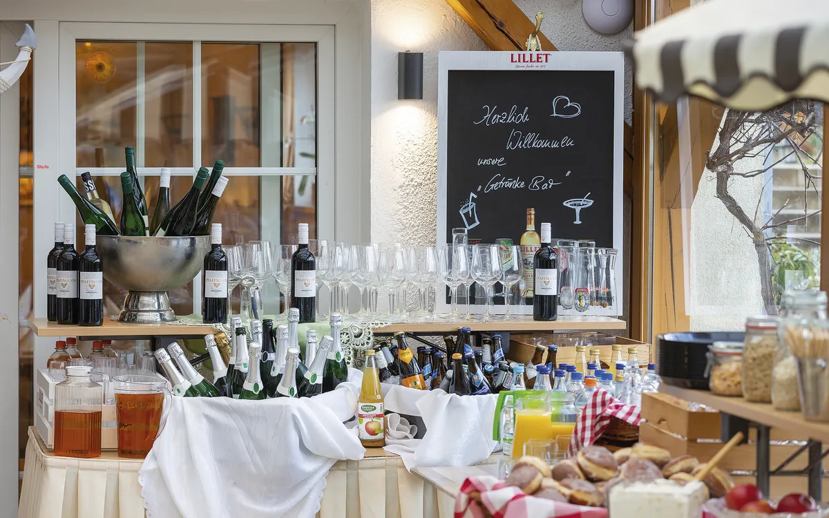Buffet-Tisch mit Weinflaschen, Gläsern und Brotkorb in einem rustikalen Ambiente.
