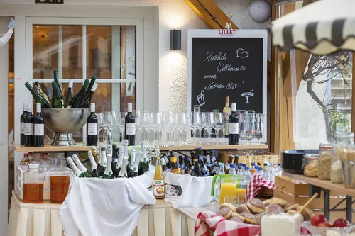 Buffet-Tisch mit Weinflaschen, Gläsern und Brotkorb in einem rustikalen Ambiente.