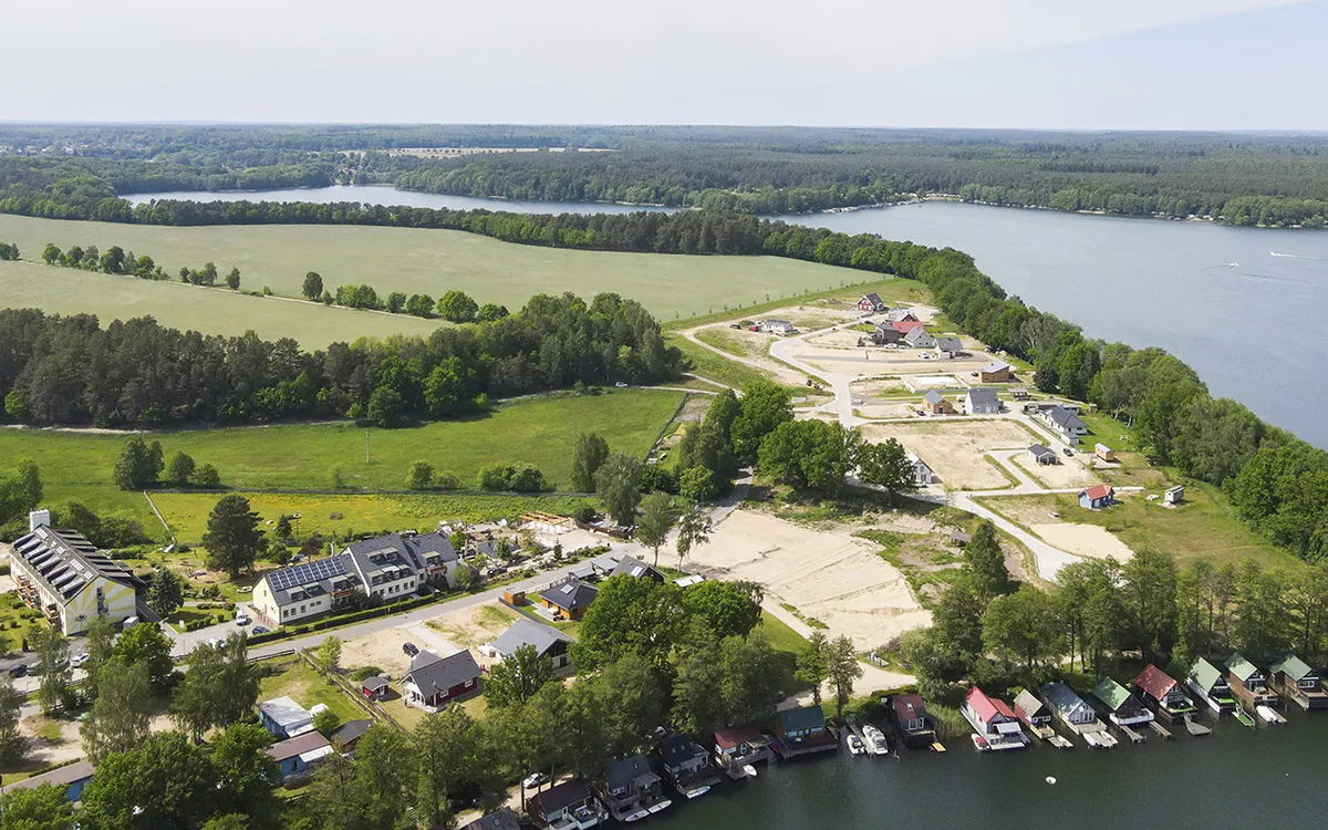 Luftaufnahme von Landschaft mit Feldern, Wald und angrenzendem See.