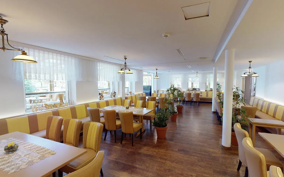 Helles Hotelrestaurant mit gelben Stühlen und Holzfußboden.
