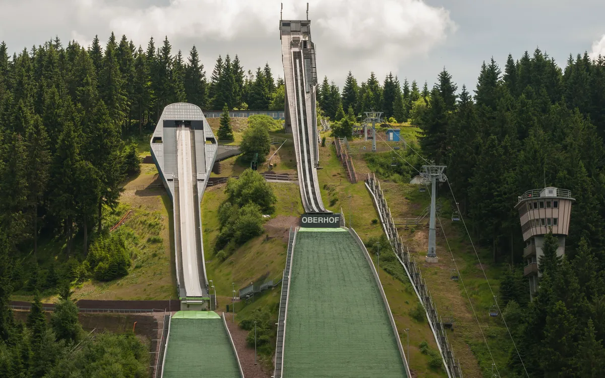 Sprungschanzen in einer bergigen Waldlandschaft mit dem Namen "Oberhof" auf einer der Anlauframpe.