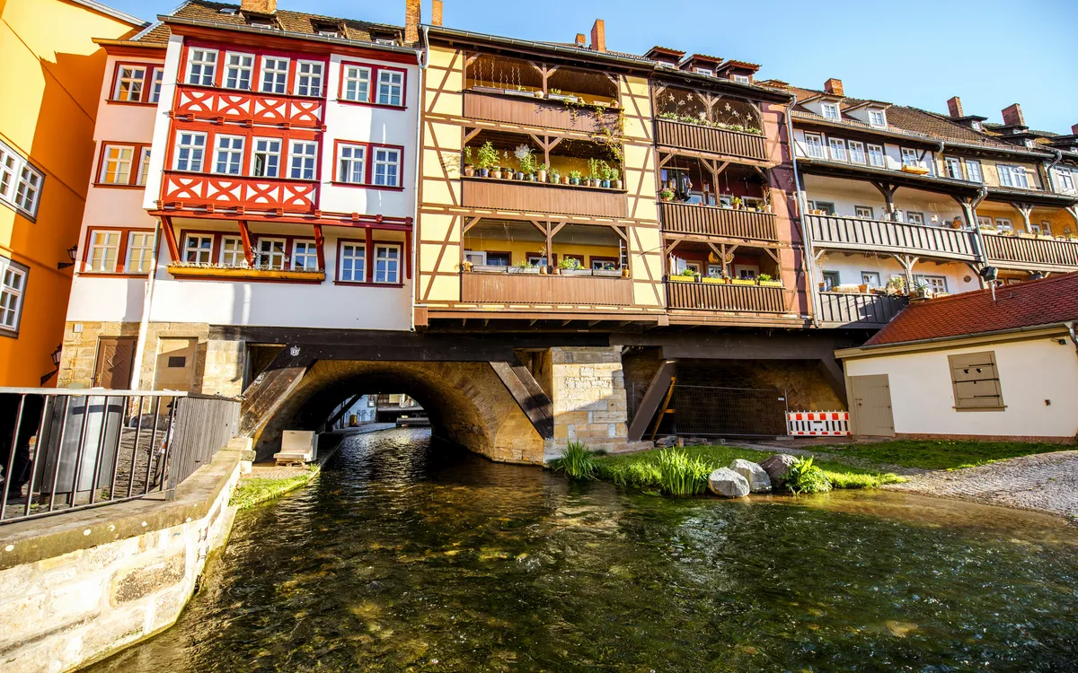Fachwerkhäuser auf Brücke über einen Fluss bei Sonnenschein.