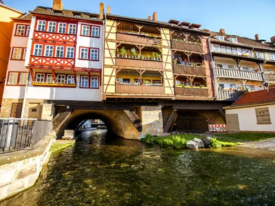 Fachwerkhäuser auf Brücke über einen Fluss bei Sonnenschein.