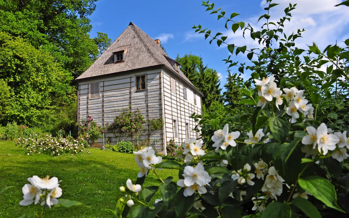 Fachwerkhaus im Garten mit blühenden Sträuchern im Vordergrund