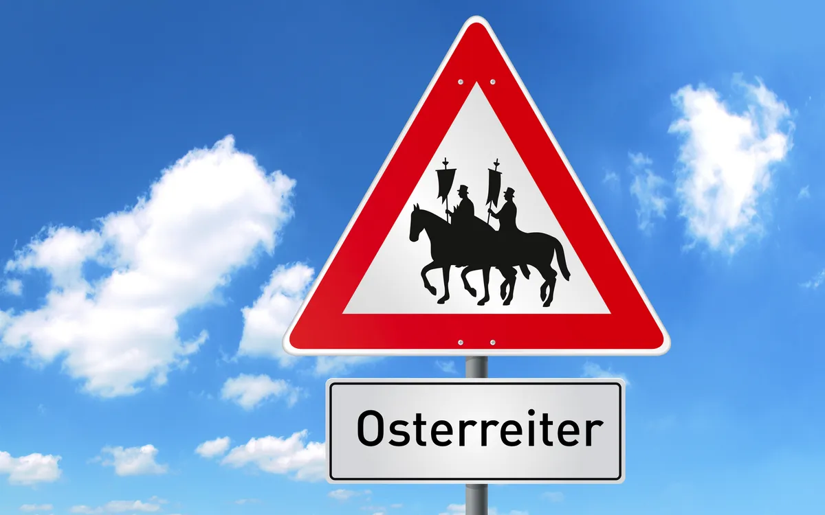 Schild mit Osterreiter-Symbol vor blauem Himmel