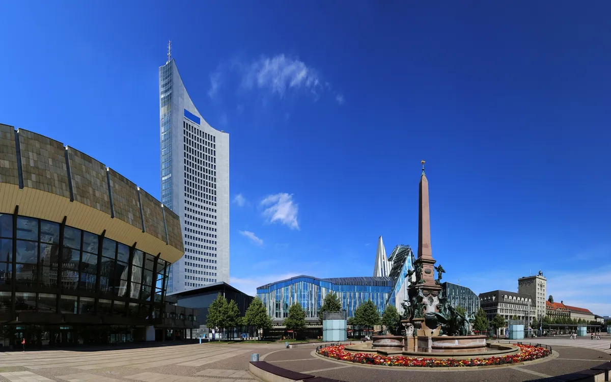 Platz mit Brunnen und modernen Gebäuden unter blauem Himmel